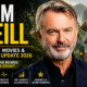 Sam Neill posing in front of a Jurassic Park-inspired background for his 2026 career and health update article.